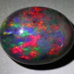 Natural gemstone black opal on gray background